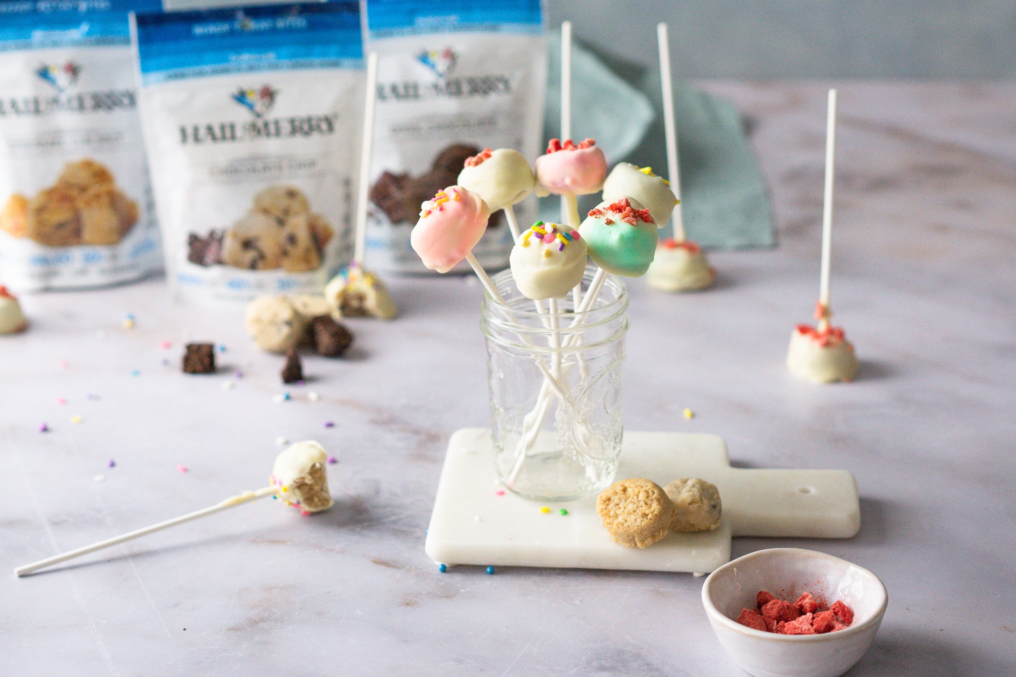 Coconut cookie dough pops made with plant-based cookie dough dipped in vegan white chocolate.  Topped with natural colored sprinkles and freeze-dried strawberries.